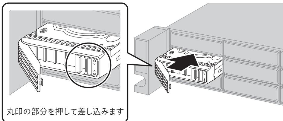 Diagram showing a new drive being inserted into an empty bay. A circular callout on the left shows a close-up of the drive's handle, with a circle highlighting the latch area. A large black arrow on the right points to the drive being pushed into the bay. Below the callout, the text '丸印の部分を押して差し込みます' (Push the circled part to insert) is present.
