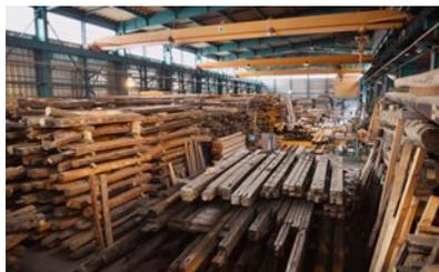 Interior view of a large warehouse storing numerous stacks of old wood.