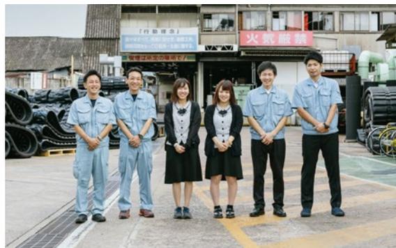 Group photo of six employees of Fukuyama Rubber Corporation standing in front of a building.